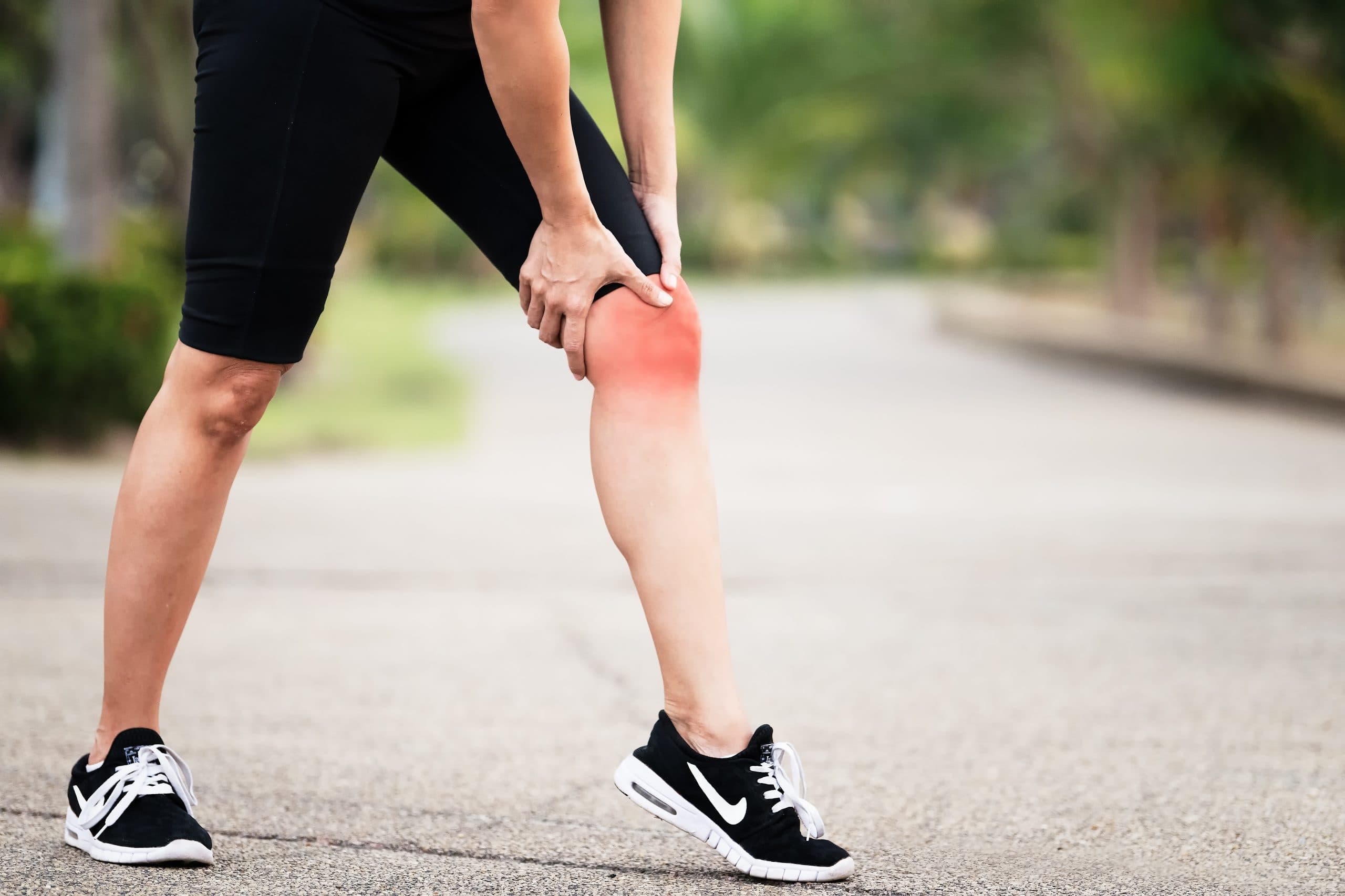 Runner holding a painful red knee outdoors